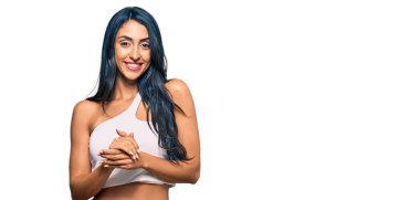 Güzel İspanyol kadın, günlük kıyafetler giyip ellerini birleştiriyor ve gülümseyerek gevşemiş ve neşeli gülümsüyor. Başarı ve iyimserlik 