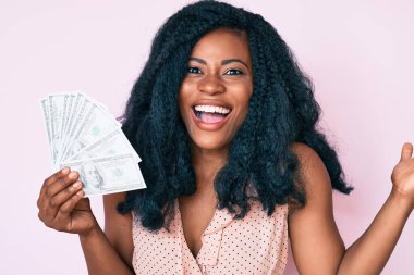 Dolarları tutan güzel Afrikalı kadın zaferi mutlu bir gülümsemeyle kutluyor ve kazanan el kaldırarak ifade ediyor. 