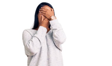 Uzun saçlı, günlük kıyafetler giyen, gözlerini ve ağzını elleriyle kapatan İspanyol kadın şaşırmış ve şok olmuştu. duygu gizleme 