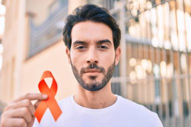 Şehirde turuncu kurdele tutan ciddi bir suratı olan genç bir İspanyol..