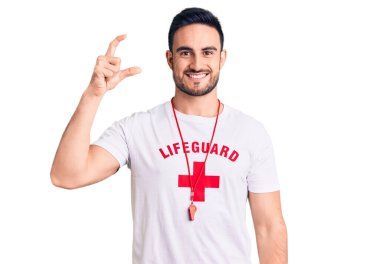 Cankurtaran üniforması giyen, gülümseyen, kendine güvenen, el hareketleriyle hareket eden, parmaklarıyla işaret eden ve kameraya bakan genç yakışıklı bir adam. ölçüm kavramı. 