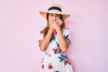 Yaz şapkası takan orta yaşlı İspanyol kadın yanlışlıkla elleri ile ağzını kapatırken şok oldu. gizli kavram. 