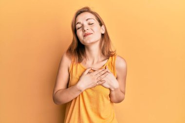 Kolsuz tişörtlü, kolsuz, göğsünde elleri kapalı, yüzünde minnet ifadesi olan beyaz bir kadın. sağlık kavramı. 