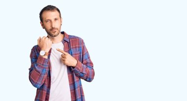 Gündelik giysiler içinde genç yakışıklı adam saati, sabırsızlığı ve rahat bir ifadeyle kameraya bakmayı işaret ediyor. 