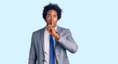 Afro saçlı, iş ceketi giyen, dudakları parmaklarında sessiz olmak isteyen yakışıklı Afro-Amerikalı bir adam. sessizlik ve gizli konsept. 