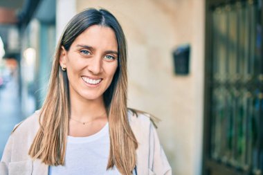 Genç beyaz kadın gülümseyerek şehirde mutlu mesut yürüyor..