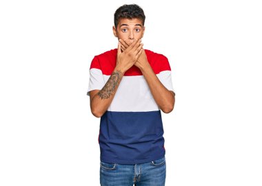 Genç, yakışıklı, Afro-Amerikalı sıradan kıyafetler giyen bir adam ağzını yanlışlıkla elleriyle kapatırken şok oldu. gizli kavram. 