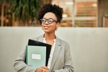 Genç Afrikalı Amerikalı iş kadını şehirde mutlu gülümsüyor..