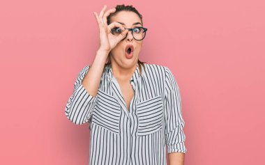 İş gömleği ve gözlük takan genç beyaz kadın şaşırmış yüz ifadesiyle şaşırmış ve parmaklarından içeri bakıyordu. İnançsız ifade. 