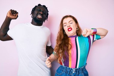 Irklar arası bir çift, günlük giysiler giyip, geriniyorlar, yorgun ve rahatlar, uykulular ve sabahın erken saatlerinde esniyorlar. 