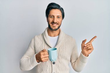 Genç İspanyol bir adam bir fincan kahve içiyor. Gülümsüyor, mutlu bir şekilde elini ve parmağını yana uzatıyordu. 