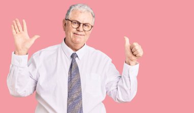 Kıdemli gri saçlı adam iş kıyafetleri giymiş ve altı numaralı parmaklarıyla işaret ederken kendinden emin ve mutlu gülümsüyor.. 