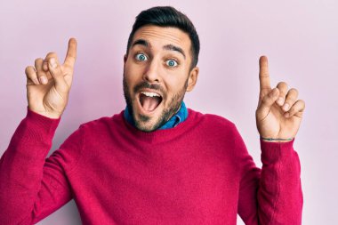 Gündelik kıyafetler giyen genç İspanyol adam şaşırmış, şaşırmış ve parmaklarıyla işaret ediyor ve kollarını kaldırıyordu.. 