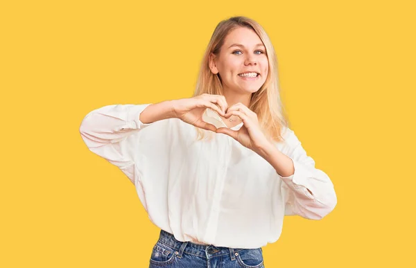 Młoda Piękna Blondynka Ubrana Luźną Koszulę Uśmiechnięta Miłością Symbolem Serca — Zdjęcie stockowe