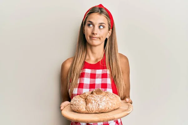 Νεαρή Ξανθιά Γυναίκα Φορώντας Στολή Φούρναρη Κρατώντας Σπιτικό Ψωμί Χαμογελώντας — Φωτογραφία Αρχείου