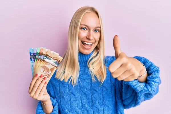 Menina Loira Jovem Segurando Dólares Canadenses Aprovando Fazer Gesto Positivo — Fotografia de Stock