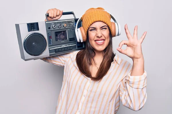 若い美しいブルネットの女性がヴィンテージのBoomboxとヘッドフォンを使用して音楽に耳を傾けます指でOkサインをします 笑顔優しいジェスチャー優れたシンボル — ストック写真