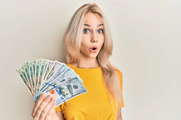 Beautiful Caucasian Blonde Girl Holding Dollars Scared Amazed Open Mouth — Foto de Stock