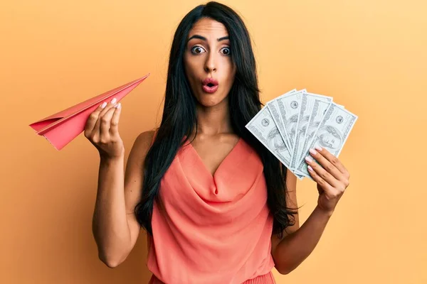 Beautiful Hispanic Woman Holding Paper Plane Dollars Afraid Shocked Surprise — Stock Photo, Image
