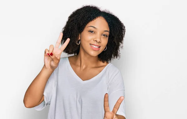 若いアフリカ系アメリカ人の女の子は 勝利のサインを行う指を示すカメラに笑みを浮かべてカジュアルな服を着ている — ストック写真