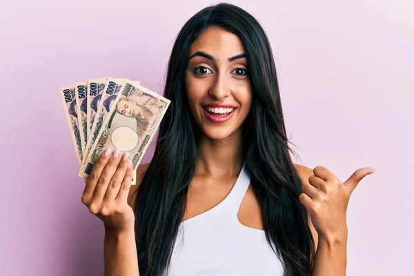 일본엔 지폐를 아름다운 스페인 여인이 입으로 행복하게 웃으며 옆으로 손가락을 — 스톡 사진