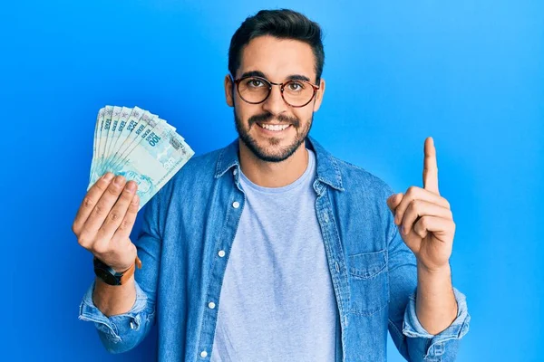 Joven Hispano Sosteniendo 100 Billetes Reales Brasileños Sonriendo Con Una —  Fotos de Stock