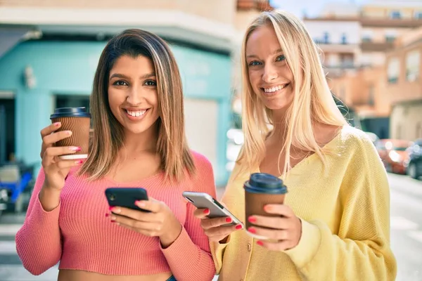2人の美しく若い女の子の友人が一緒にスマートフォンを使って街で楽しんでいます — ストック写真