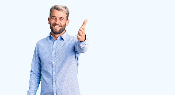 年轻英俊的金发男子穿着优雅的衬衫 友善地微笑 握手表示问候和欢迎 成功的商业 — 图库照片