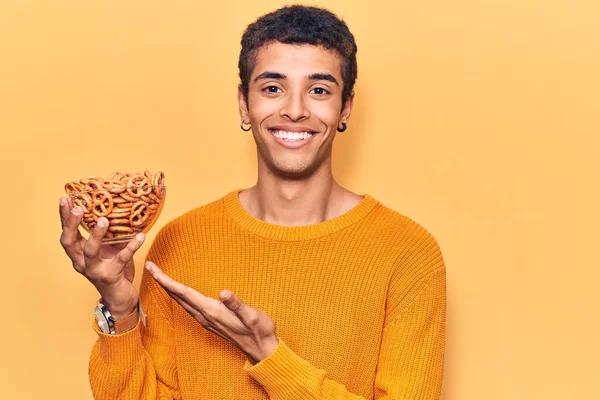 Young African Amercian Man Holding Pretzels Looking Positive Happy Standing — Stock Photo, Image