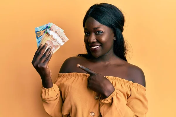Afričanky Mladá Žena Drží Kanadské Dolary Úsměvem Šťastný Ukazující Rukou — Stock fotografie