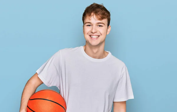 若いです白人男性保持バスケットボールボール見て正と幸せな立ちと笑顔で自信を持って笑顔示す歯 — ストック写真