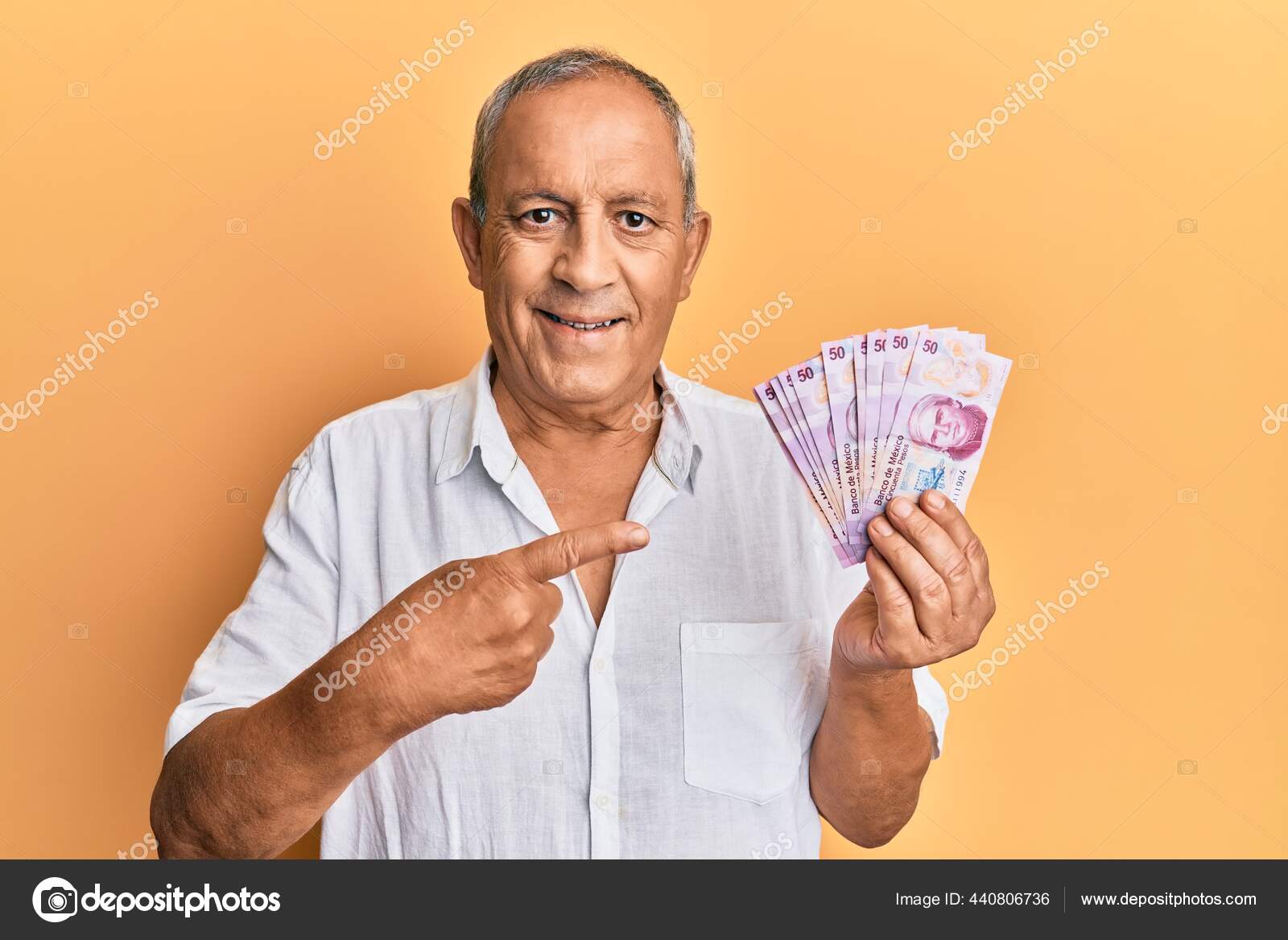 英俊而成熟的男人手里拿着50枚墨西哥比索钞票高兴地微笑着手指手画脚——图库图片© Krakenimages.com #440806736