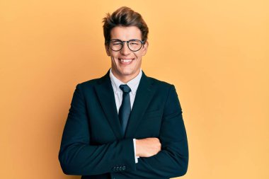 İş elbisesi giymiş yakışıklı beyaz bir adam ve kollarını kavuşturup kameraya bakarken gülümseyen mutlu bir yüz. pozitif kişi. 