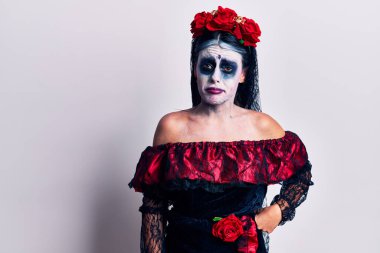 Ölü makyajlı Meksika günü giyen genç bir kadın üzgün ve endişeli, sinirli ve korkmuş bir şekilde ağlıyor. hüzünlü ifade. 