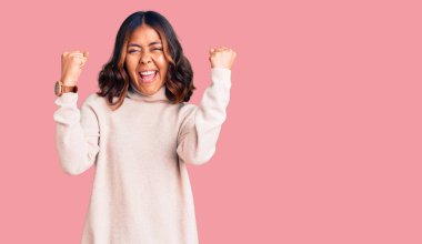 Balıkçı yaka kazak giyen genç ve güzel, melez bir kadın kızgın ve kızgın yumruklar sallıyor öfkeyle bağırırken. öfke ve agresif konsept. 