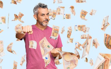 Orta yaşlı, gri saçlı, günlük kıyafetler giymiş dövüşmek için yumruk sallayan saldırgan ve öfkeli saldırı, tehdit ve şiddet uygulayan bir adam.