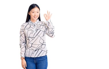 Gündelik tişört giyen genç, güzel Çinli kadın gülümsüyor ve el ve parmaklarıyla 