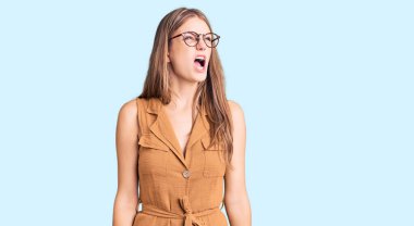 Genç, güzel, sarışın bir kadın. Günlük kıyafetler ve gözlük takıyor. Öfkeli ve öfkeli çığlıklar atıyor. öfke ve agresif konsept. 