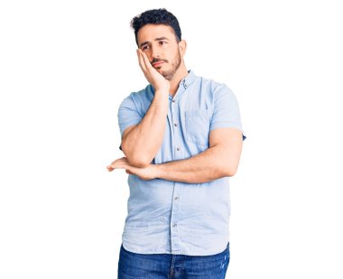 Günlük kıyafetler giyen genç İspanyol adam kollarını kavuşturarak depresyondan sıkılmış ve yorgun görünüyor.. 