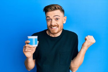 Kulak kiri tutan genç kızıl saçlı adam gururla haykırıyor, zaferi ve başarıyı kutluyor. 