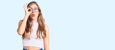 Gündelik kıyafetler ve gözlük takan güzel beyaz bir kadın şaşırmış yüz ve gözlerle parmaklarından bakıyor. İnançsız ifade. 