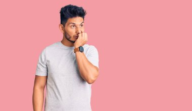 Yakışıklı Latin Amerikalı rahat tişört giyen stresli ve gergin görünen elleri ağızdan tırnak yiyen genç adam. anksiyete. 