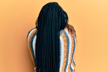 Young black woman with braids wearing casual winter sweater hugging oneself happy and positive from backwards. self love and self care  clipart