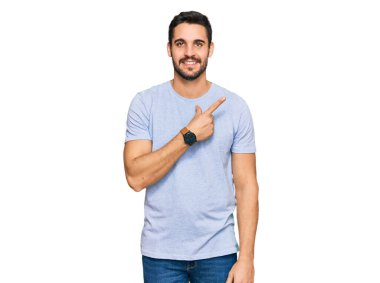 Gündelik kıyafetler giyen, neşeli, yüzünde gülümseme olan genç İspanyol adam mutlu ve doğal bir ifadeyle elini ve parmağını kaldırdı. 