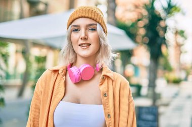 Şehirde kulaklık takan genç sarışın kız..