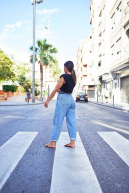 Güzel, genç bir bayan şık kıyafetler giyiyor ve caddenin ortasında duruyor.