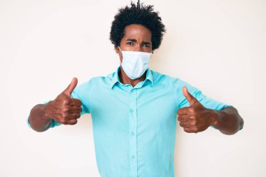 Yakışıklı Afro saçlı, tıbbi maske takan, ağzı açık, şüpheci ve alaycı görünen Afro-Amerikan bir adam. 