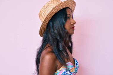 Bikini giyen ve şapka takan genç Hintli kız, rahat bir görünüm takınıyor, kendine güvenen bir gülümsemeyle doğal bir yüz ifadesi sergiliyor.. 