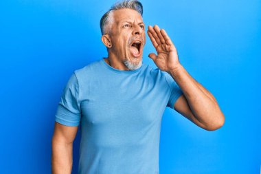 Orta yaşlı, gri saçlı, günlük kıyafetler giyen, el ele tutuşup bağıran bir adam. iletişim konsepti. 