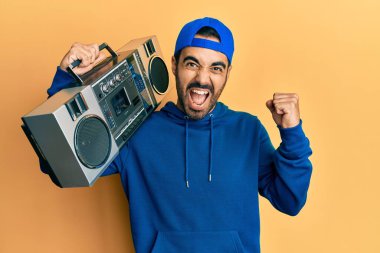 Latin kökenli genç adam, müzik dinlerken gururla haykırıyor, zaferi kutluyor ve kollarını kaldırarak çok heyecanlanıyor. 